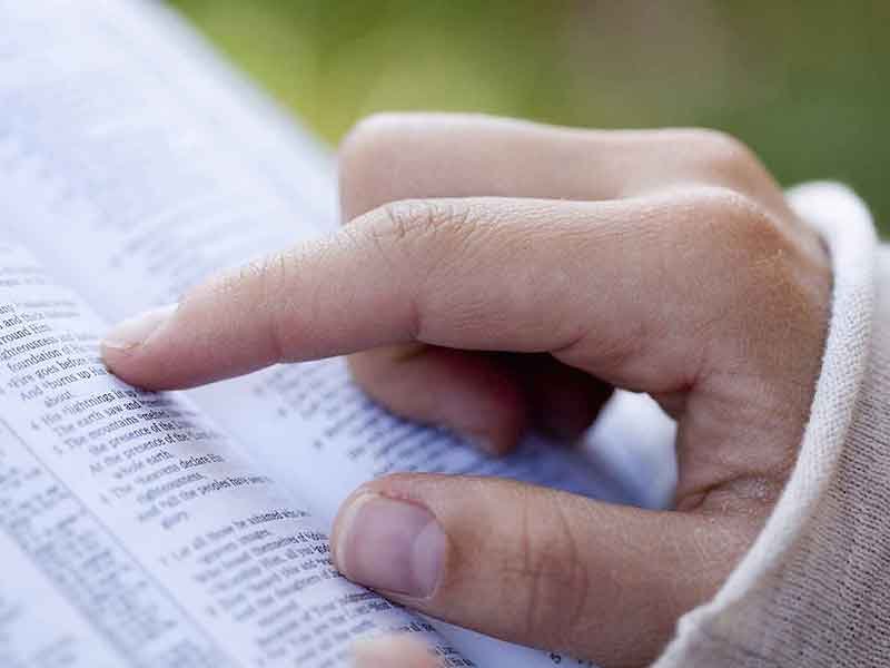 A hand following along in a bible.